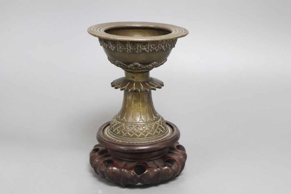 A 19th century Himalayan bronze urn, on carved stand, height 18cm